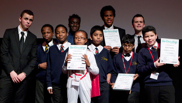 A large group of young people on a stage holding awards and certificates