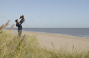 Long shot of a beach showing a teenage boy holding aloft a baby