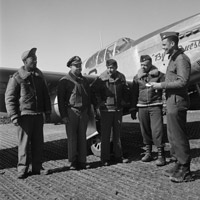 Five black pilots standing in front of a plane