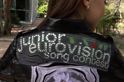 back of girl's jacket brightly embroidered with the words Junior Eurovision Cong Contest