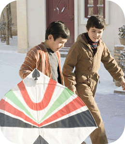 Medium shot of 2 boys walking with a kite through a snowy street
