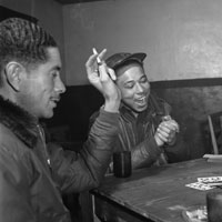 Two African American airmen playing cards around a table, one is smoking